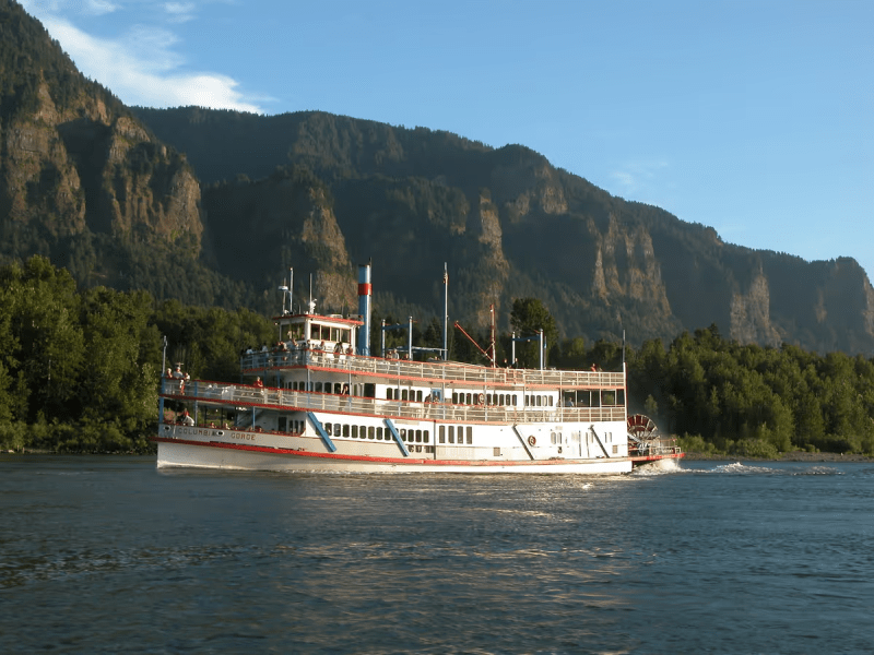 a large boat in a body of water with a mountain in the background
